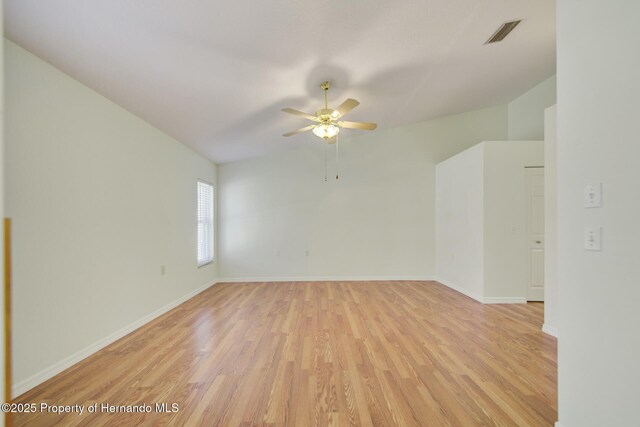 spare room with ceiling fan, light wood-type flooring, visible vents, and baseboards