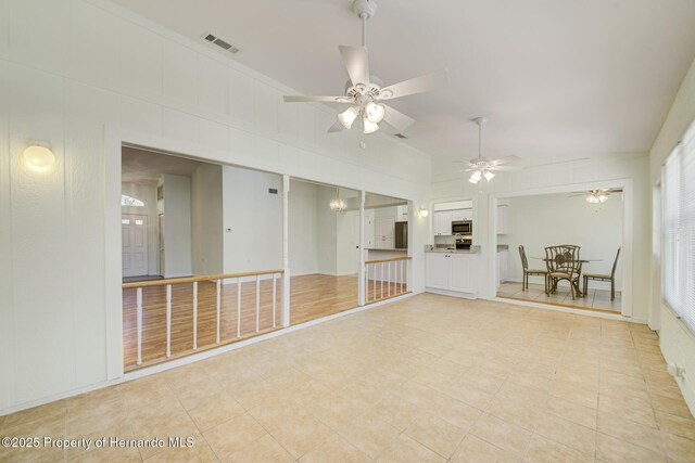 empty room featuring visible vents, ornamental molding, and ceiling fan with notable chandelier