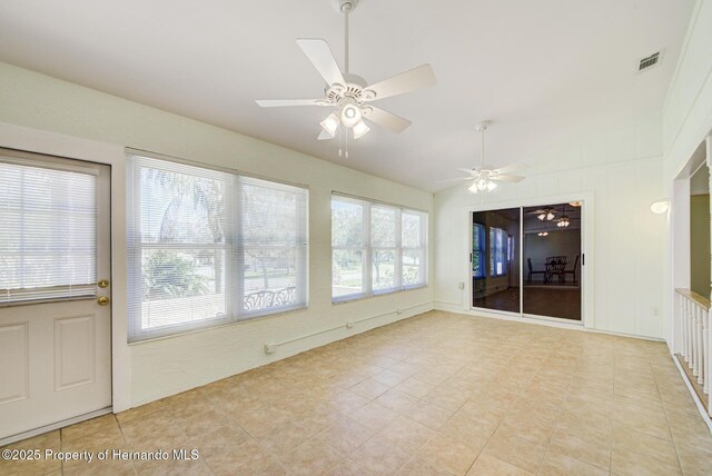 unfurnished sunroom with a healthy amount of sunlight, visible vents, vaulted ceiling, and ceiling fan