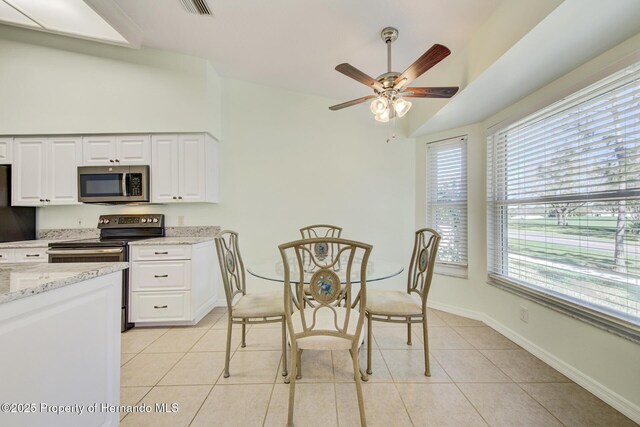 kitchen with light stone counters, stainless steel appliances, white cabinetry, light tile patterned flooring, and baseboards