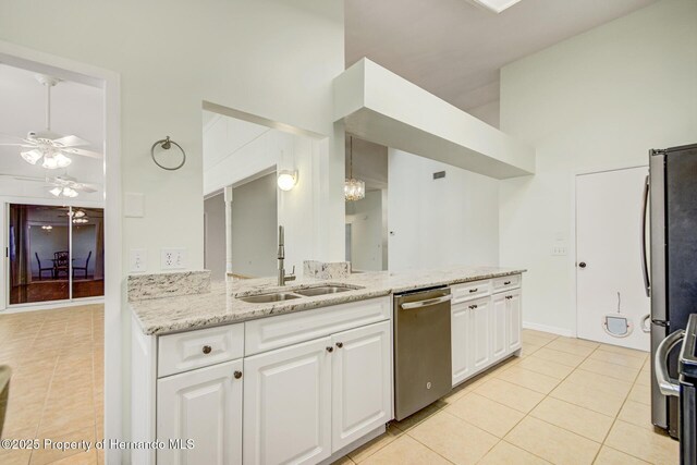 kitchen featuring light tile patterned floors, stainless steel appliances, a sink, white cabinetry, and light stone countertops