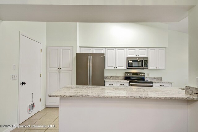 kitchen with light tile patterned floors, stainless steel appliances, white cabinetry, and light stone countertops