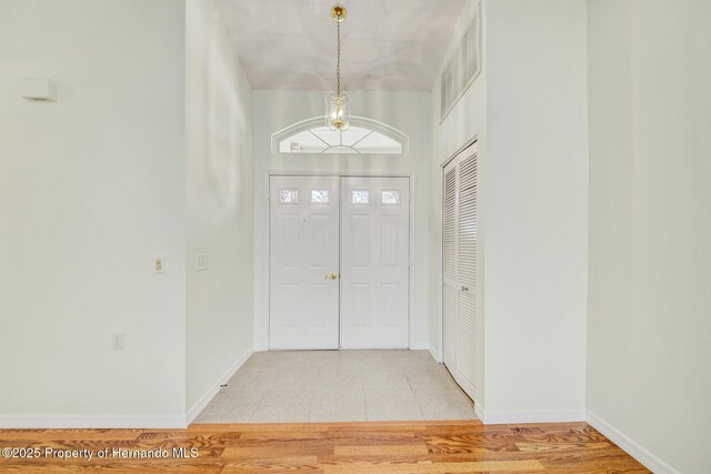 foyer featuring light wood-style floors, visible vents, and baseboards