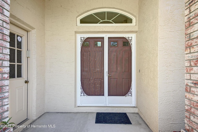 property entrance featuring brick siding and stucco siding