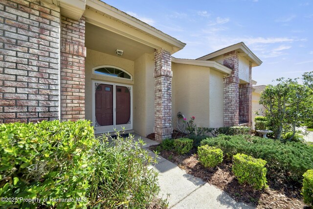 doorway to property with brick siding and stucco siding