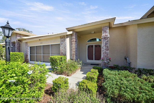 property entrance featuring a garage, brick siding, and stucco siding