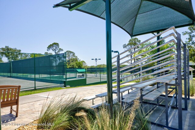 view of community featuring a tennis court and fence