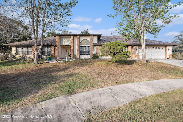 view of front of home with a garage, a front yard, brick siding, and driveway