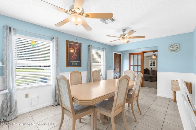 dining area with french doors, a wainscoted wall, light tile patterned floors, visible vents, and a textured ceiling