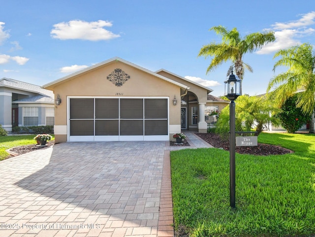 view of front of property with a front lawn, decorative driveway, an attached garage, and stucco siding