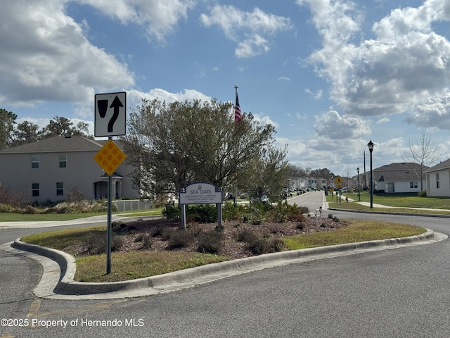 view of street featuring street lighting, traffic signs, a residential view, and curbs