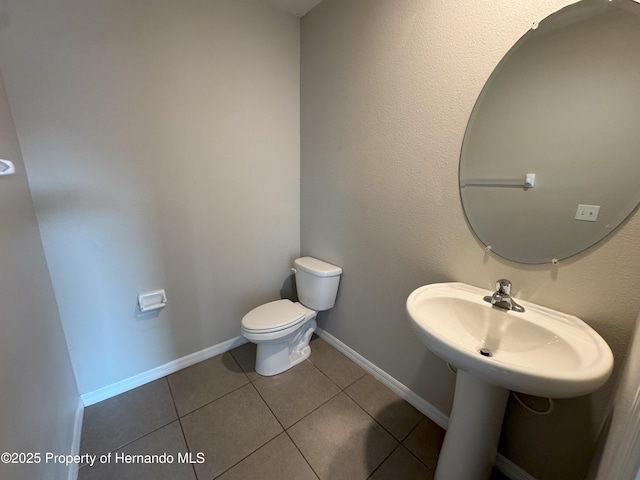 half bathroom featuring toilet, tile patterned flooring, and baseboards