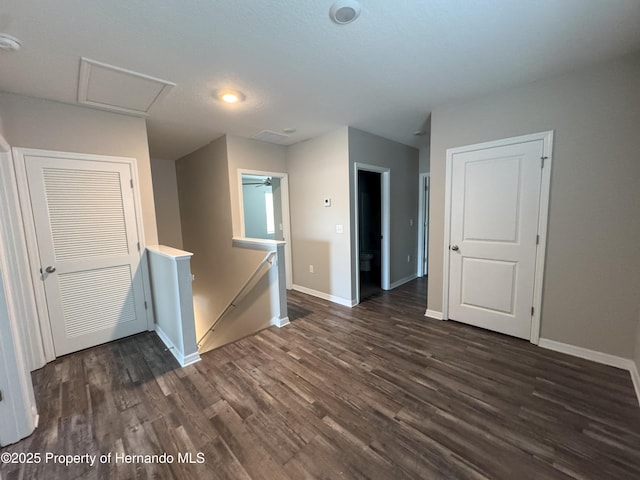 spare room with attic access, dark wood-type flooring, and baseboards
