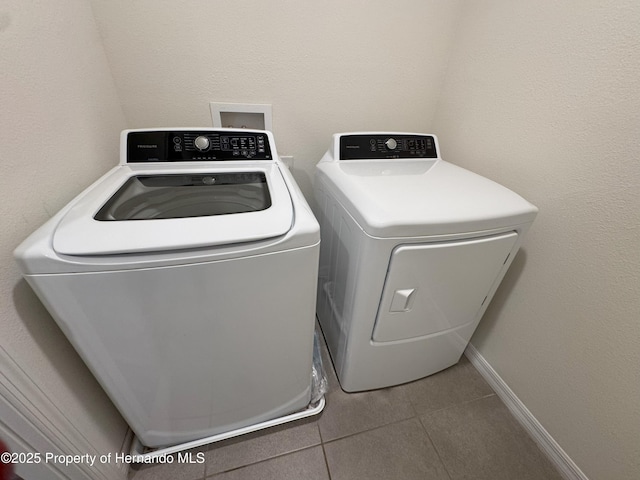 laundry room featuring tile patterned flooring, laundry area, baseboards, and washing machine and clothes dryer