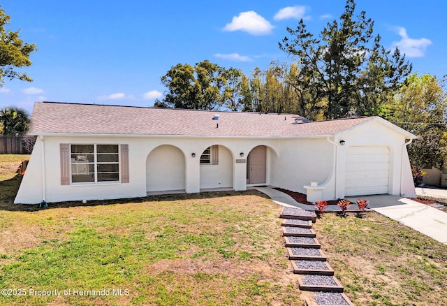 view of front of property featuring stucco siding, driveway, a front lawn, and a garage