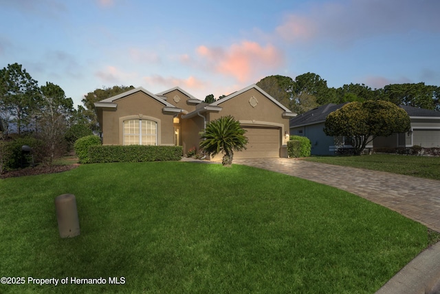 ranch-style house with a yard, a garage, driveway, and stucco siding