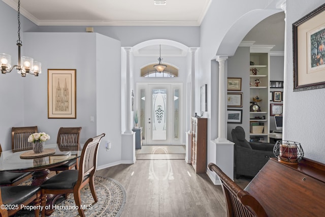 entryway with decorative columns, arched walkways, wood finished floors, and ornamental molding