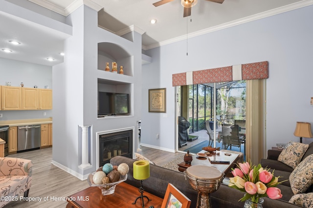 living room featuring light wood-style flooring, a ceiling fan, and ornamental molding