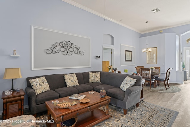 living room featuring a notable chandelier, wood finished floors, visible vents, and ornamental molding