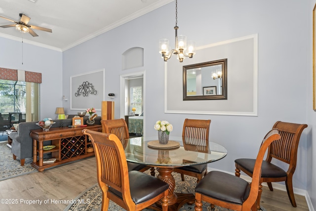 dining area featuring ceiling fan with notable chandelier, wood finished floors, and ornamental molding