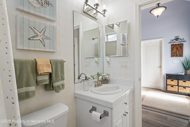 bathroom featuring toilet, wood finished floors, and vanity