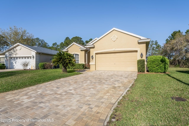 single story home with stucco siding, decorative driveway, a front yard, and an attached garage