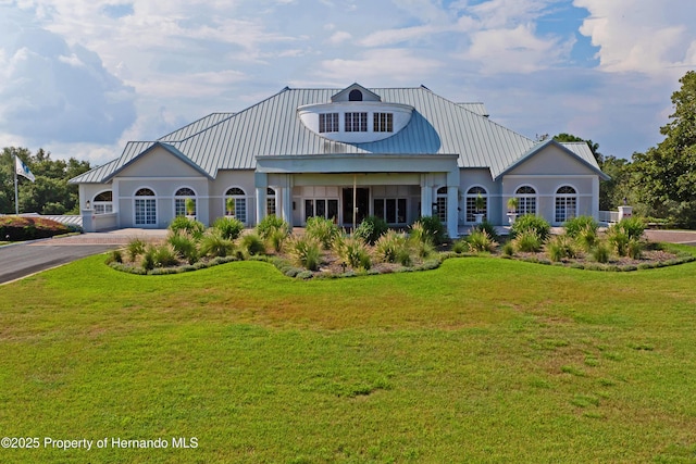 view of front of house featuring metal roof, driveway, and a front yard