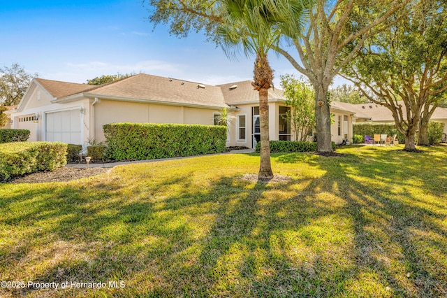 ranch-style home with a garage, a front lawn, and stucco siding