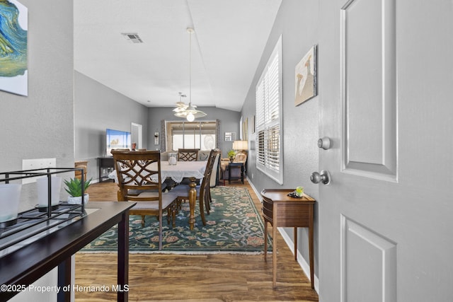 dining area featuring dark wood-style floors, lofted ceiling, visible vents, and baseboards