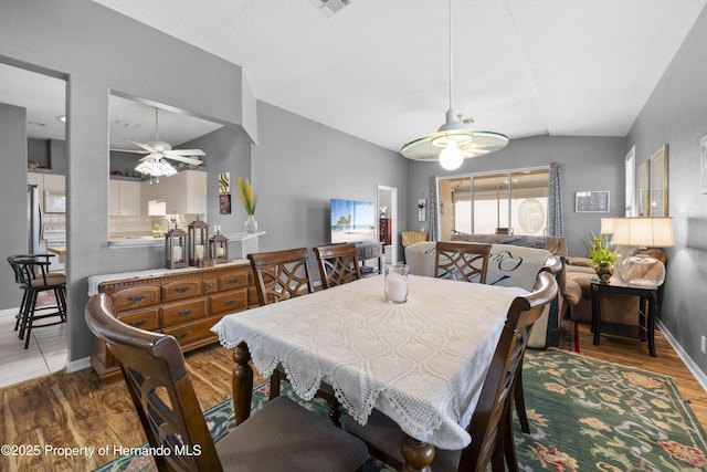 dining area featuring lofted ceiling, wood finished floors, a ceiling fan, and baseboards