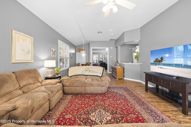 living area with baseboards, visible vents, a ceiling fan, lofted ceiling, and wood finished floors