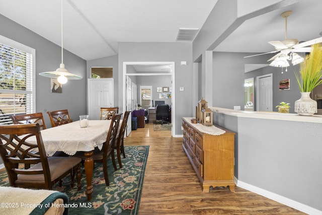 dining room with a wealth of natural light, dark wood-style flooring, vaulted ceiling, and baseboards