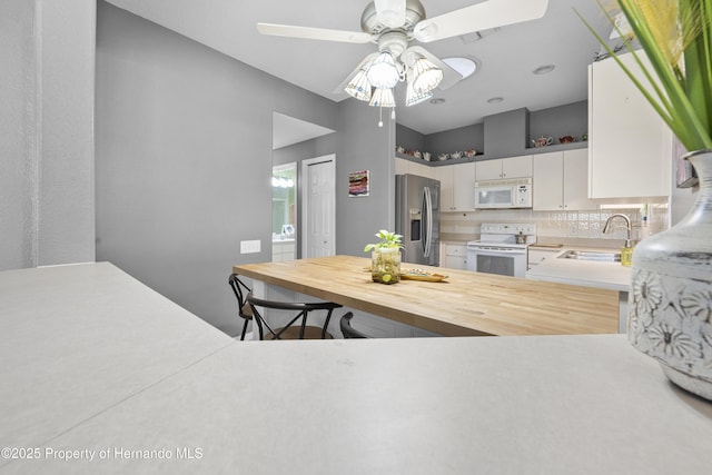 kitchen with tasteful backsplash, butcher block counters, white cabinets, a sink, and white appliances