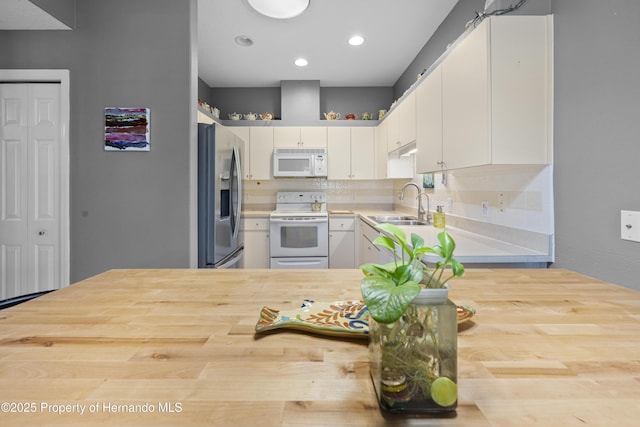 kitchen with white appliances, white cabinetry, and light countertops