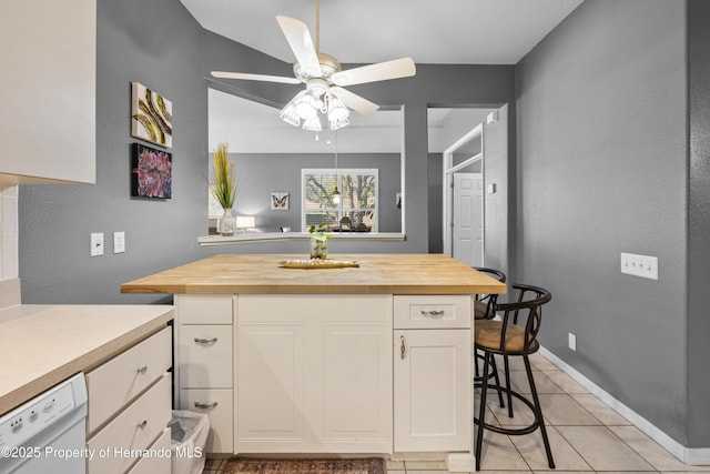 kitchen featuring white cabinets, dishwasher, wood counters, a kitchen island, and a kitchen bar