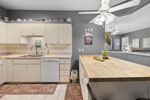 kitchen featuring light tile patterned floors, white dishwasher, a sink, wood counters, and tasteful backsplash