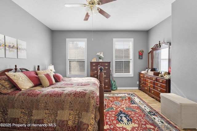 bedroom featuring ceiling fan, multiple windows, light wood-style flooring, and baseboards