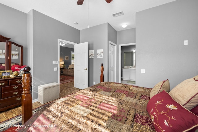 bedroom featuring a ceiling fan, visible vents, connected bathroom, and wood finished floors