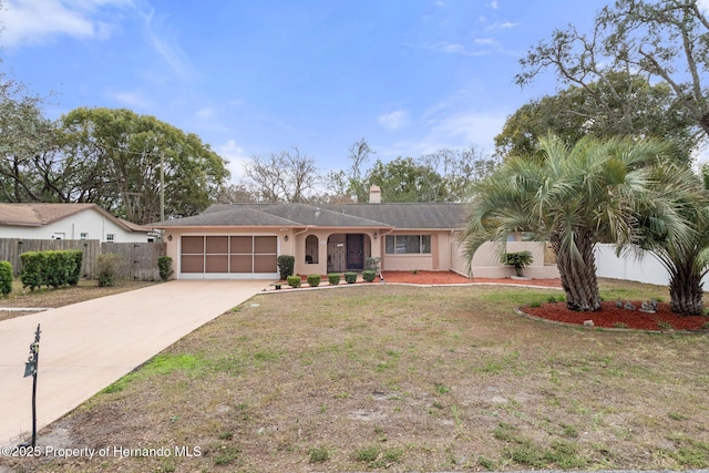 ranch-style home featuring a garage, concrete driveway, fence, a front lawn, and stucco siding