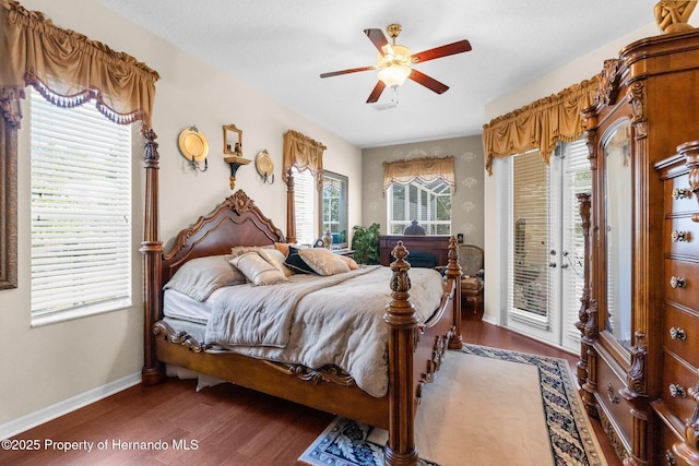 bedroom with access to outside, baseboards, multiple windows, and wood finished floors