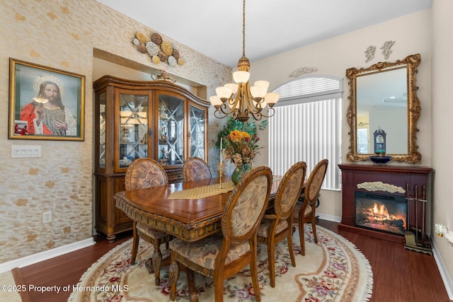 dining space with a notable chandelier, baseboards, wallpapered walls, and wood finished floors