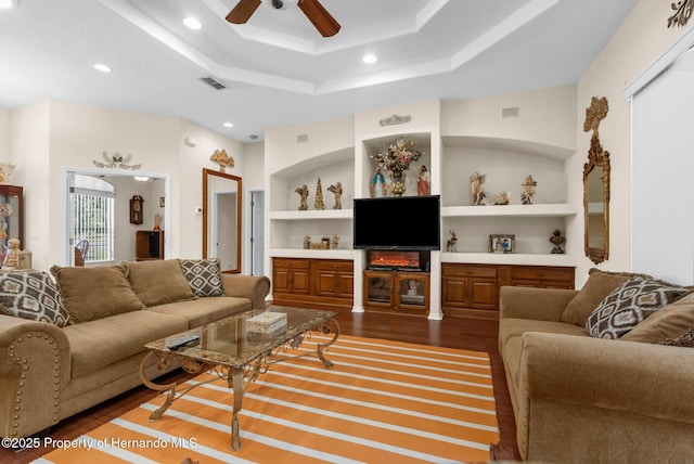 living room featuring a ceiling fan, visible vents, dark wood-style floors, built in shelves, and recessed lighting