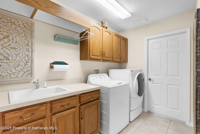 clothes washing area featuring washer and dryer, light tile patterned floors, a sink, cabinet space, and a textured ceiling