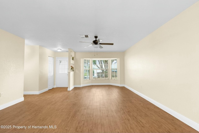 spare room with baseboards, visible vents, ceiling fan, and wood finished floors