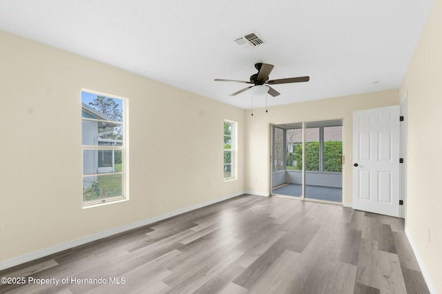 spare room featuring a ceiling fan, baseboards, visible vents, and wood finished floors