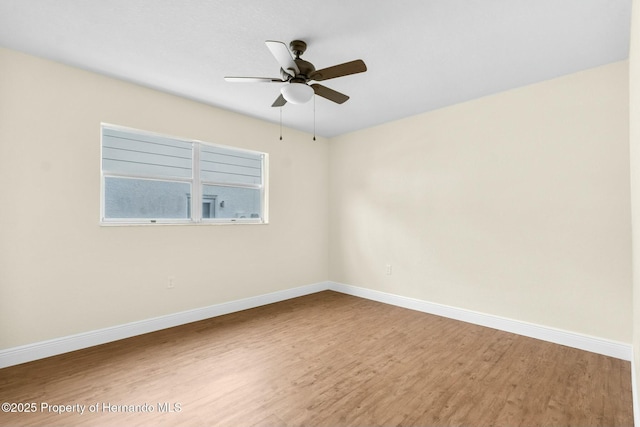 unfurnished room with wood finished floors, a ceiling fan, and baseboards