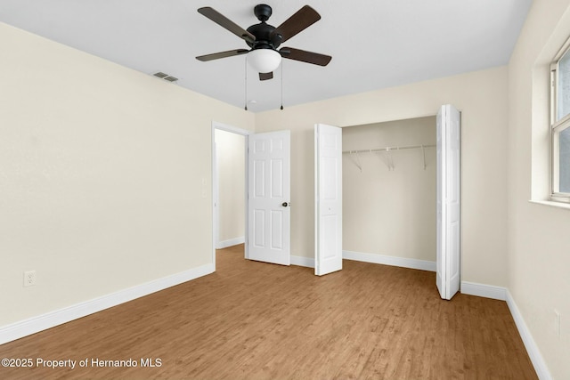 unfurnished bedroom featuring a closet, visible vents, baseboards, and wood finished floors