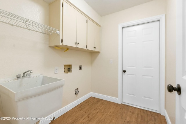 clothes washing area with hookup for a washing machine, cabinet space, a sink, electric dryer hookup, and light wood-type flooring