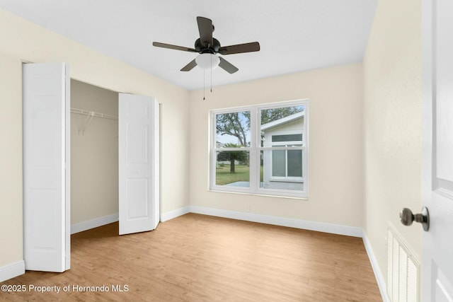 unfurnished bedroom featuring baseboards, visible vents, a ceiling fan, wood finished floors, and a closet