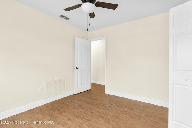 empty room featuring ceiling fan, wood finished floors, visible vents, and baseboards